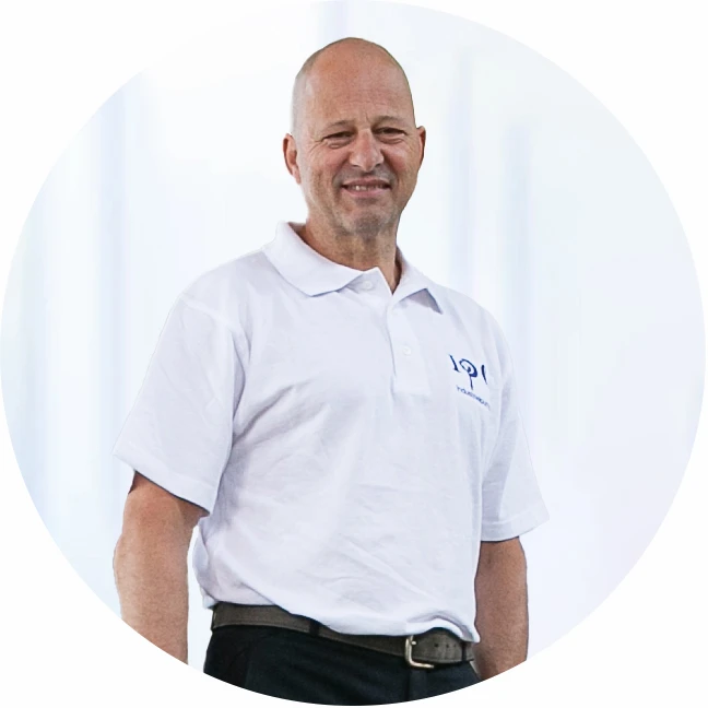 Smiling Industrial Pump Group employee in branded white polo shirt, standing in bright indoor setting